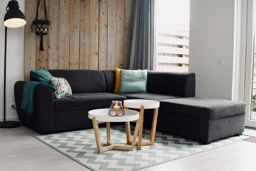 Round, wooden coffee tables in front of a black sofa