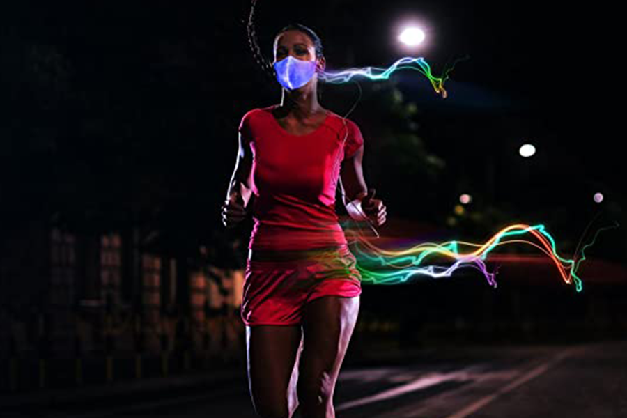 Woman running on the road and wearing red sports suit and LED light mask