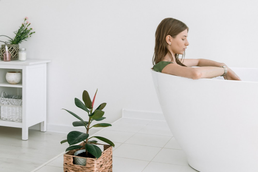 Woman in a bathtub next to a plant