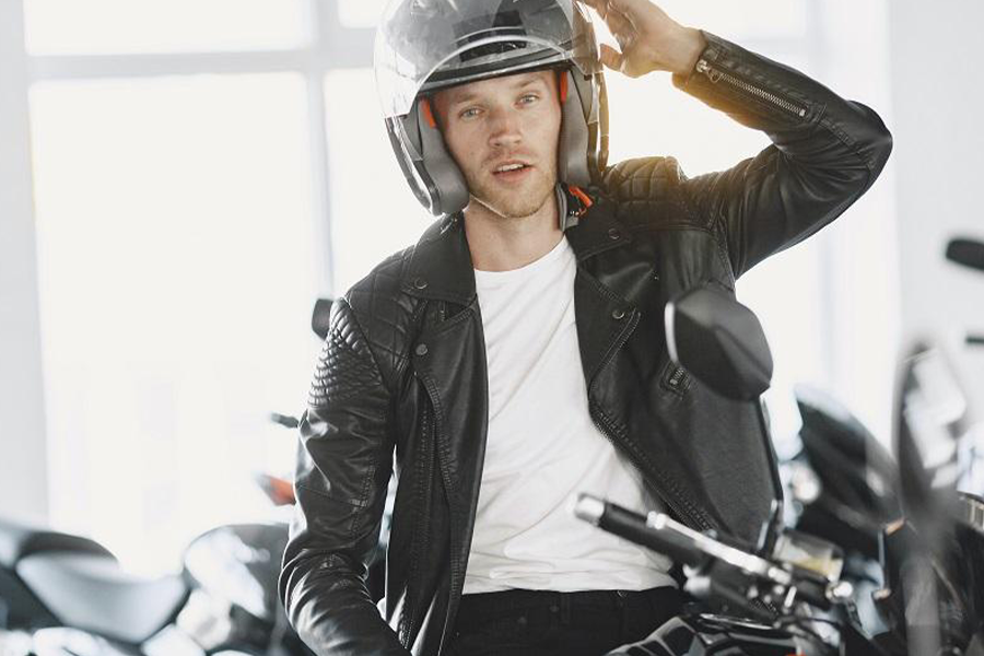 Man posing while wearing a leather jacket on a motorcycle