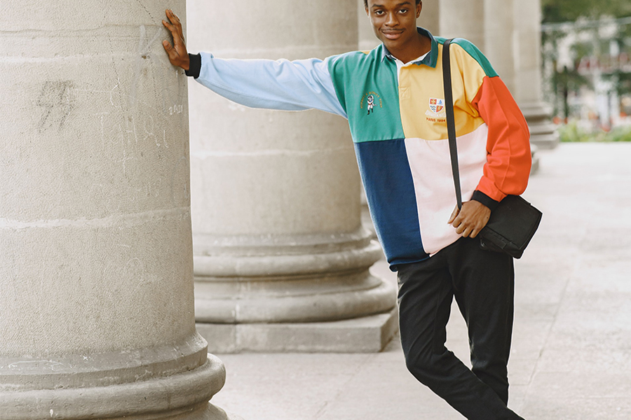 Man in multi-color long sleeve polo leaning on column