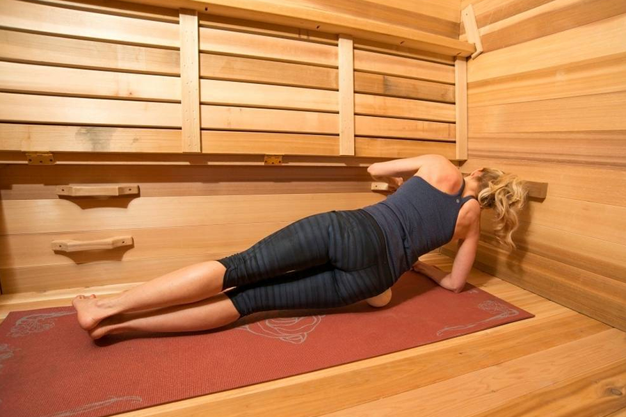 Woman doing a side plank inside a hot yoga sauna