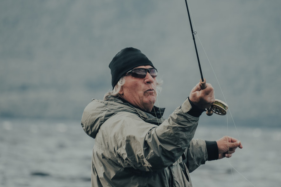 Senior citizen fishing wearing a grey fishing hoodie