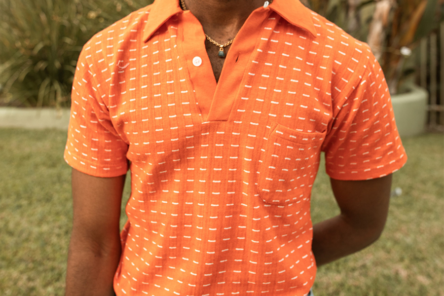 Man in orange classic polo with gray pants