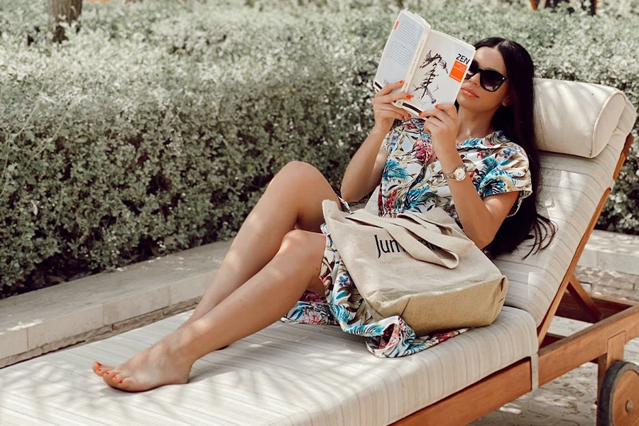 A tourist reading a novel on a customizable beach chair
