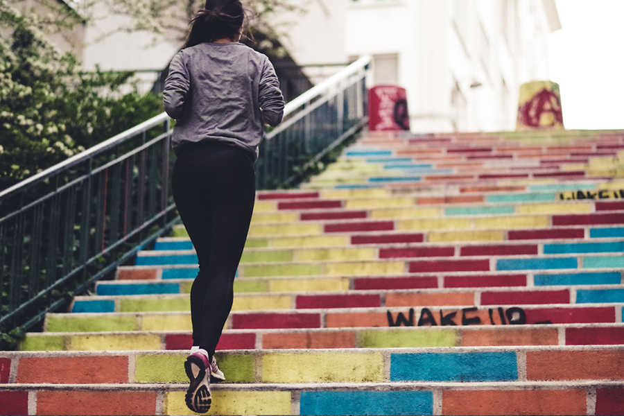 A woman running up colorful outdoor stairs in fall attire