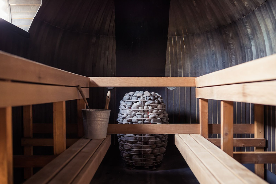 Nordic barrel sauna with seating and rocks for heat generation