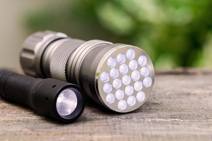 Big and small handheld flashlight against rustic background