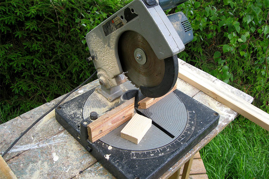 Miter saw placed on wooden table in a garden