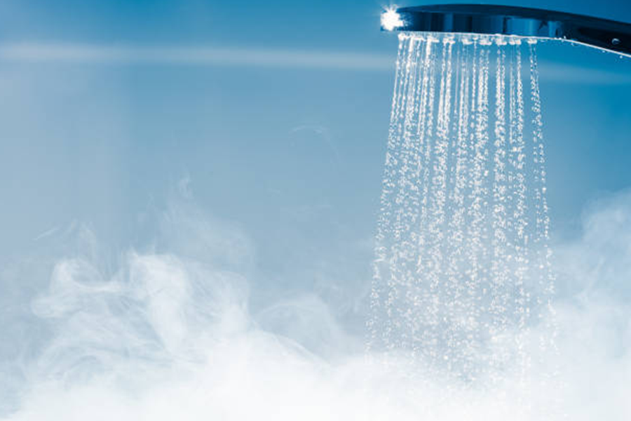 Showerhead in a blue-tiled shower room with steam