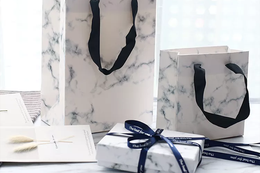Paper bags and a paper box with a versatile, white marble design