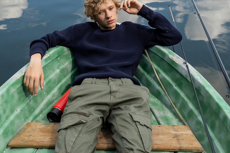 Young man in duratex fishing pants relaxing on a boat