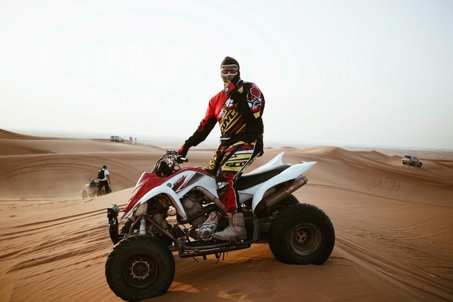 Man in red motorcycle suit posing on an ATV