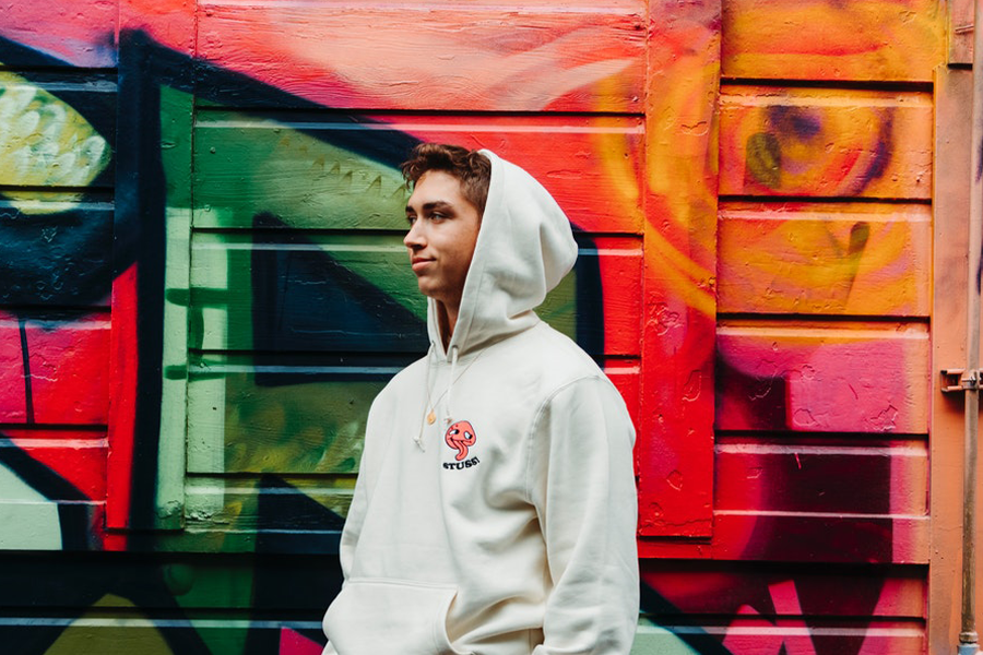 Young man in a hoodie standing by a multi-colored background