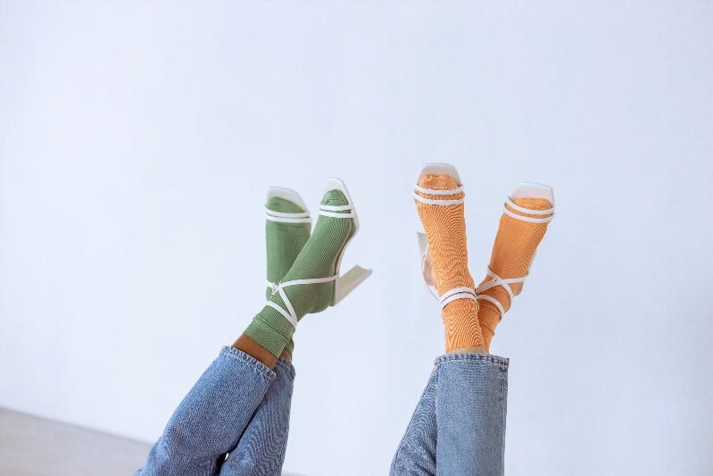Women wearing green and orange socks with white strappy heels