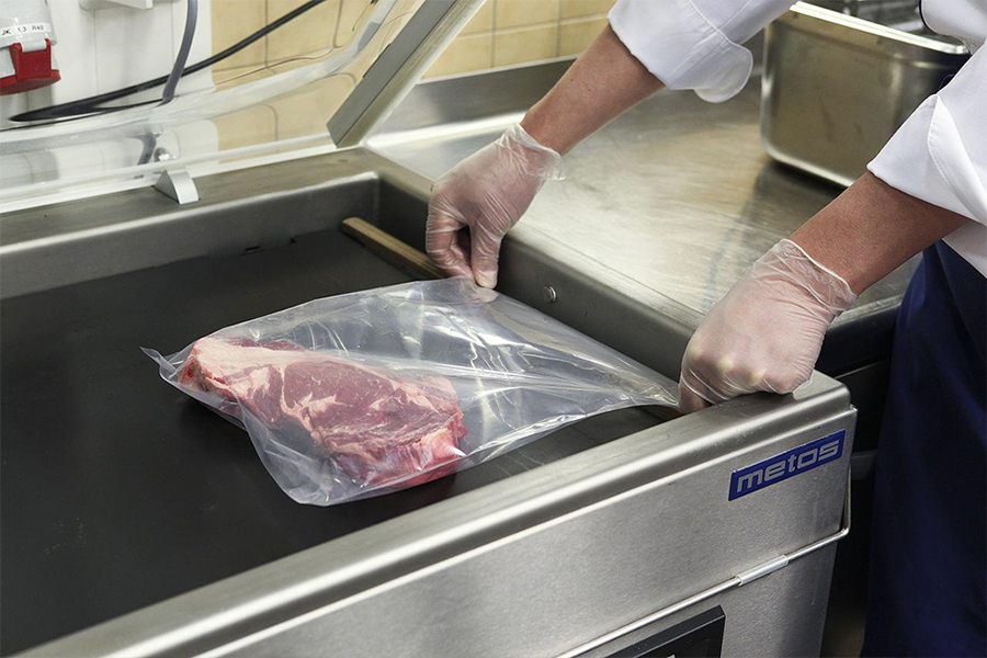 Man sealing meat with a silver packaging machine