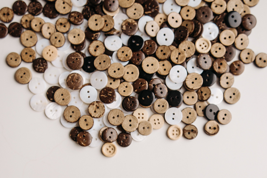 Numerous brown wooden buttons lying on a white surface