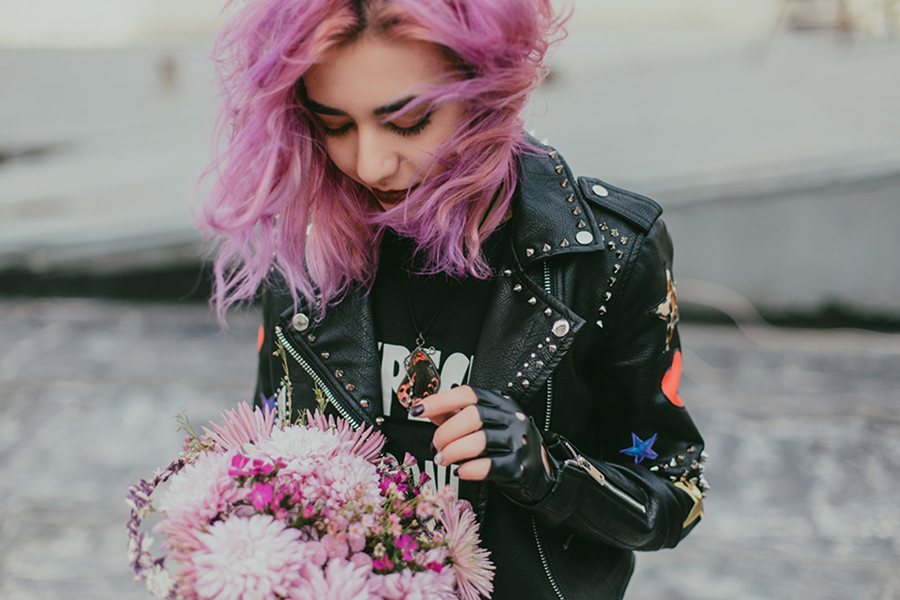 Lady with pink hair rocking black jacket with multiple logos