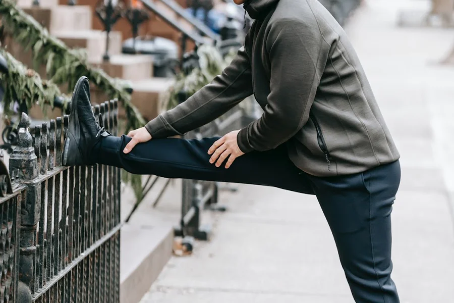 A man wearing black joggers and stretching