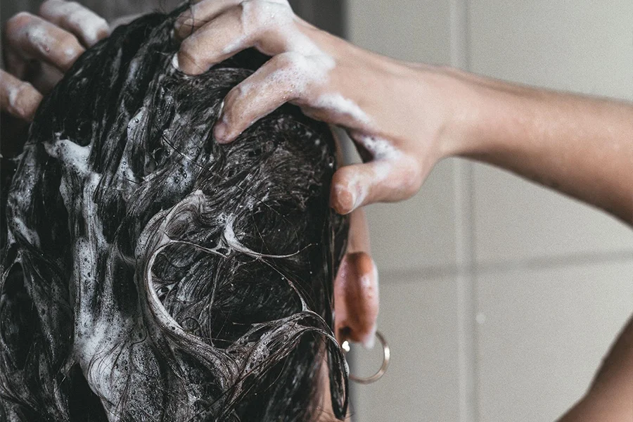 Woman washing black hair with shampoo