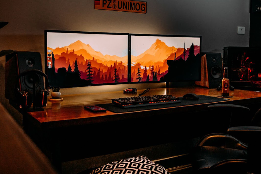 Two monitors with landscape wallpapers in a dark room