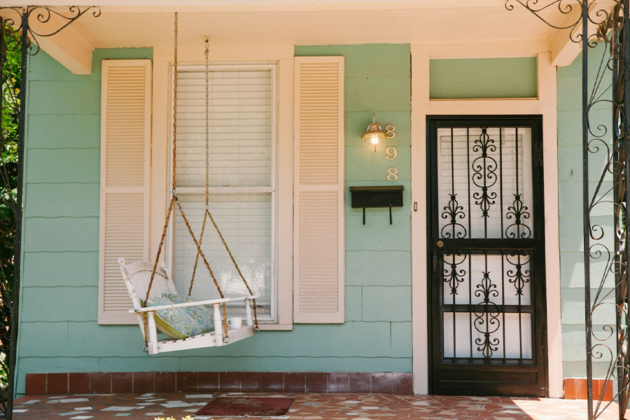 a white wooden hanging patio swing in front of window