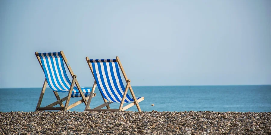 Blue and white striped beach chairs on a pebble beach
