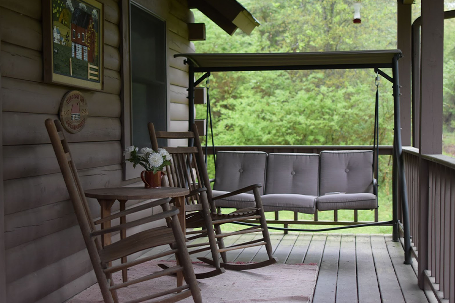 gray hanging patio swing chair with cushions on cabin patio