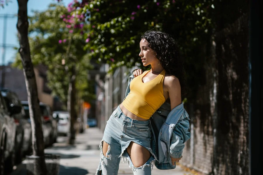 Lady in yellow tank top, denim jacket and ripped jeans