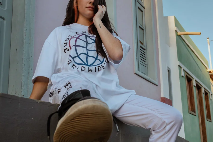 Lady sitting on a pavement with a white oversized shirt