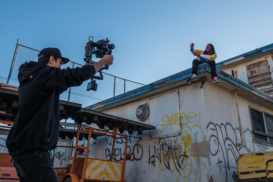 man taking video of a person on a roof