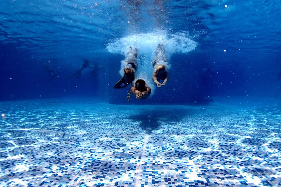 Men diving into pool with blue and white mosaic tiles