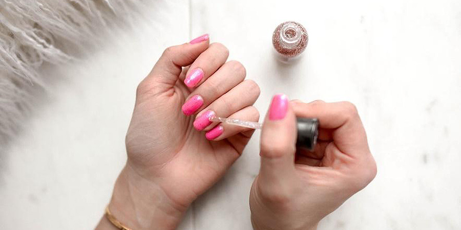 Person Applying Glitter Polish On Hot Pink Nails