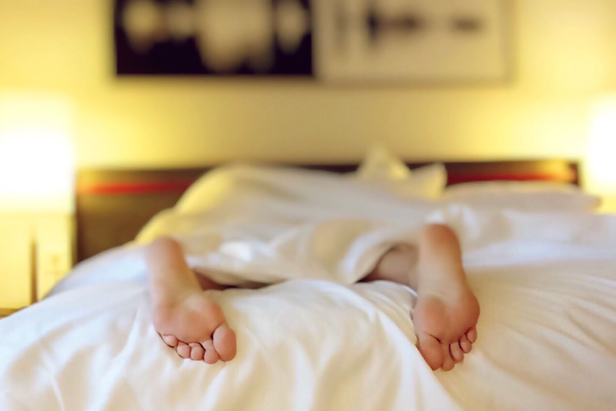 Person in bed with their feet sticking out of bedding