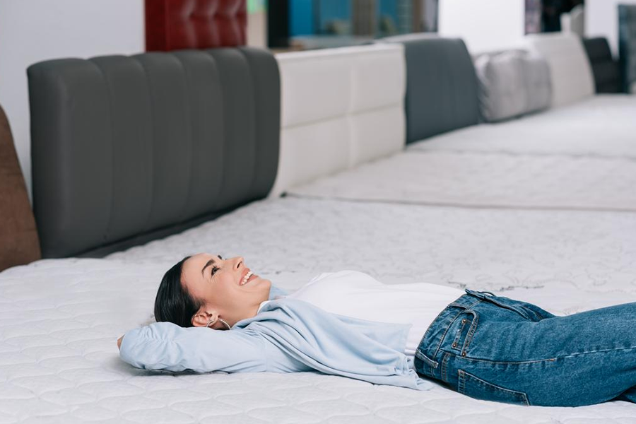 Woman lying down testing the firmness of a mattress