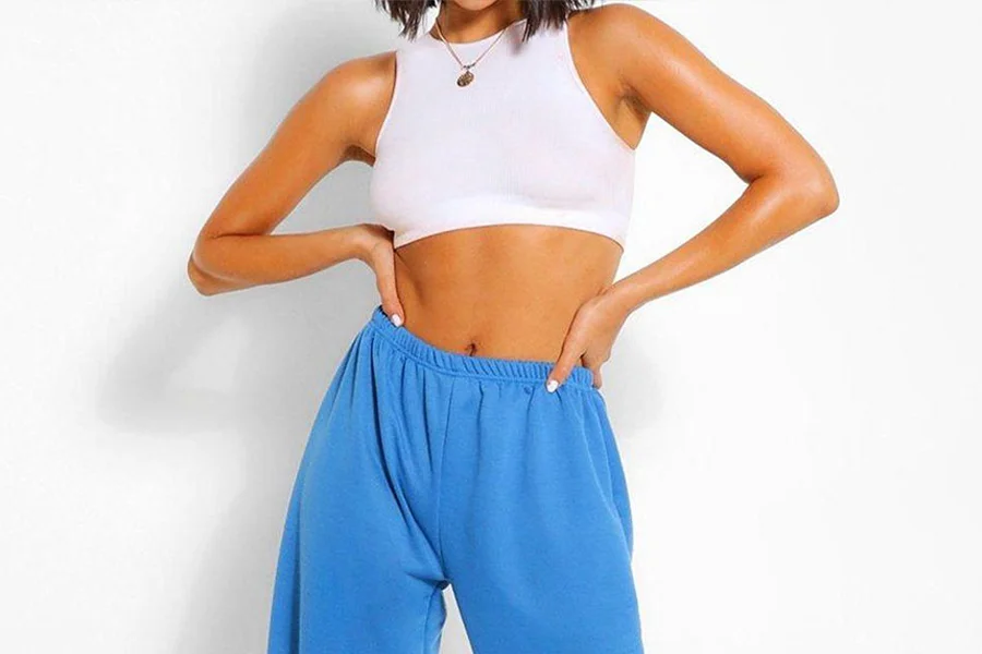Woman wearing oversized tracksuit pants with a white crop top