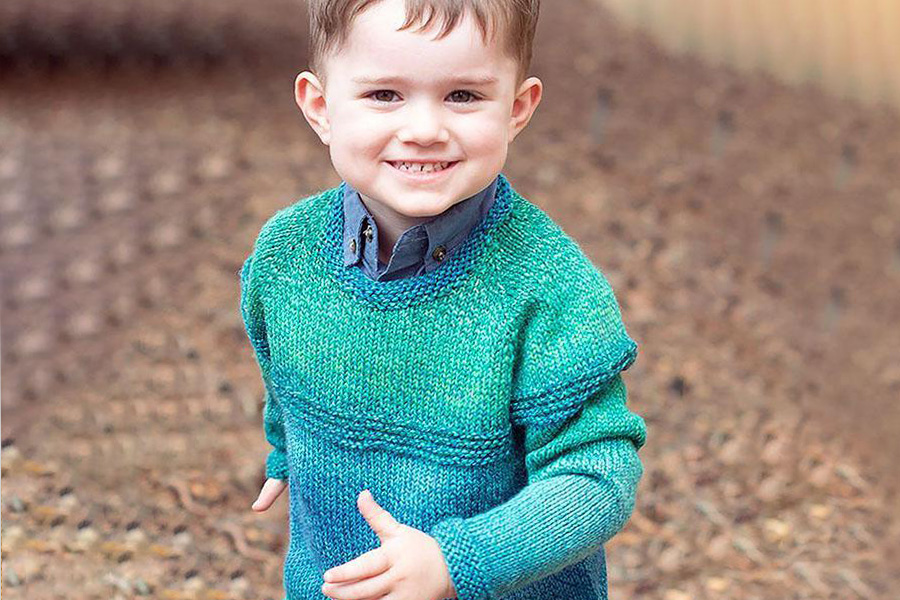 A boy in a cyan and lilac sweater