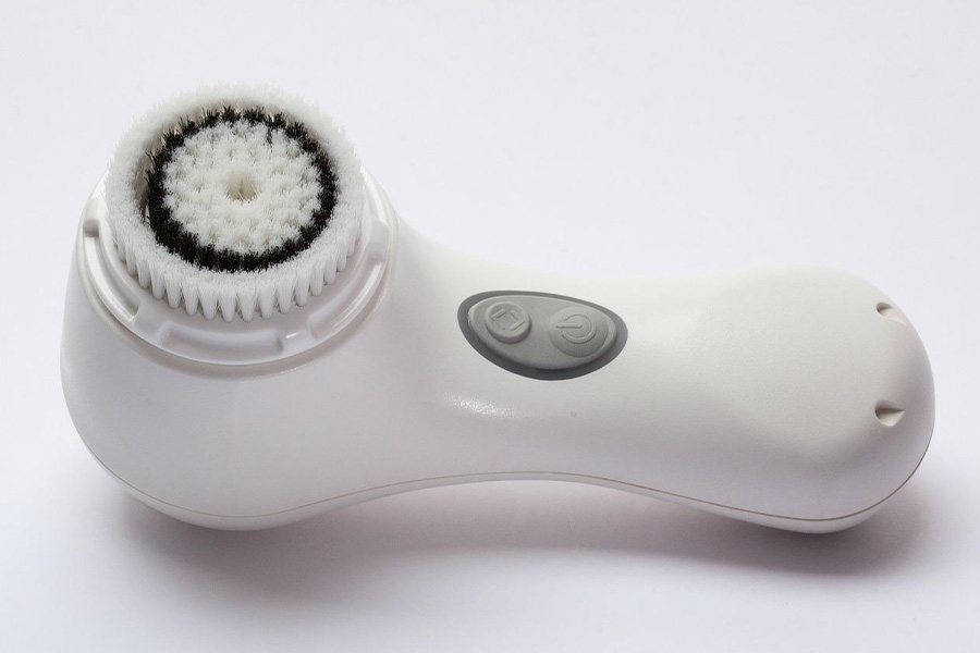 A facial cleansing brush on a white background