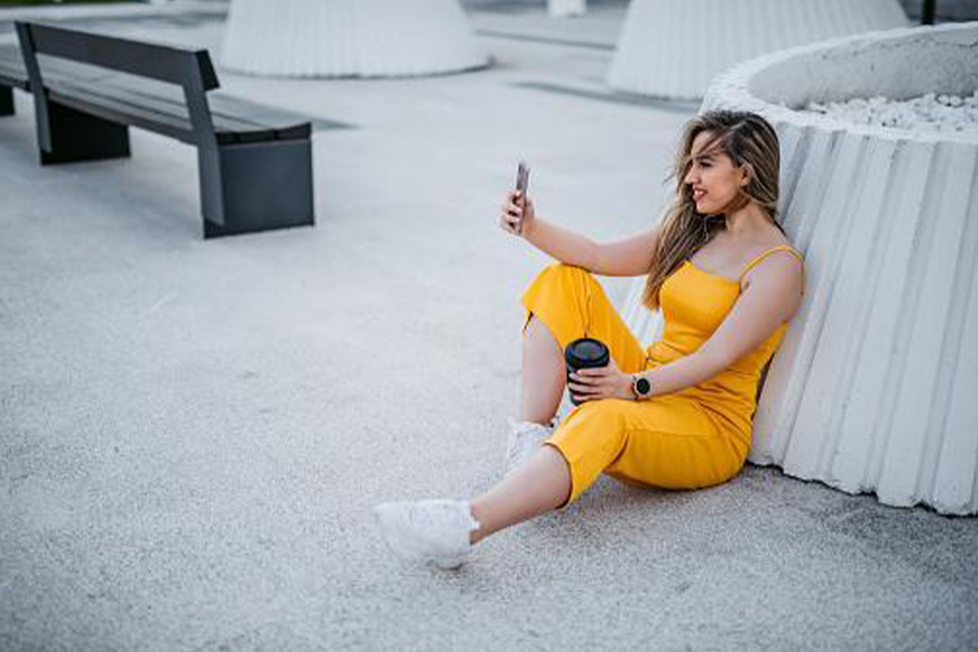 A lady wearing a yellow jumpsuit while sitting down