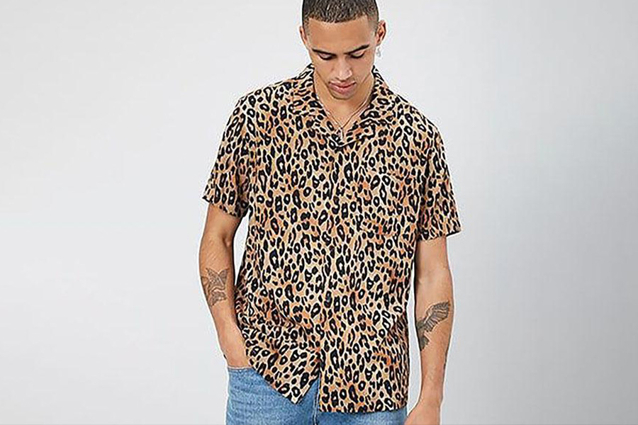 A man in leopard skin shirt and denim trousers