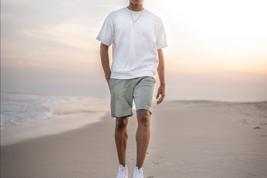 A man walking on the beach wearing shorts