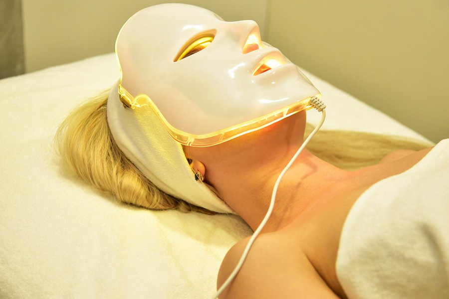 A woman getting facial treatment using an LED mask