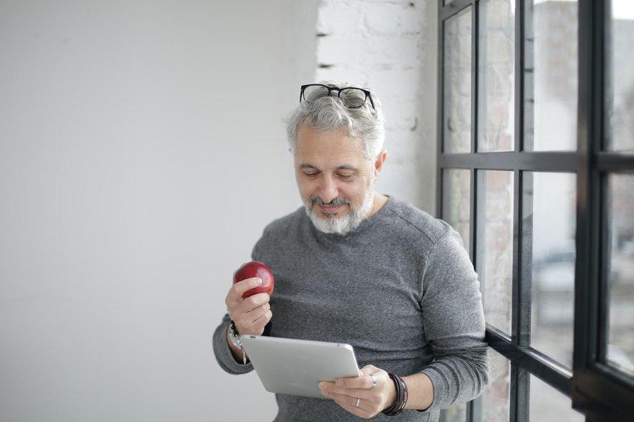 Elderly man rocking gray long-sleeved t-shirt and holding an apple