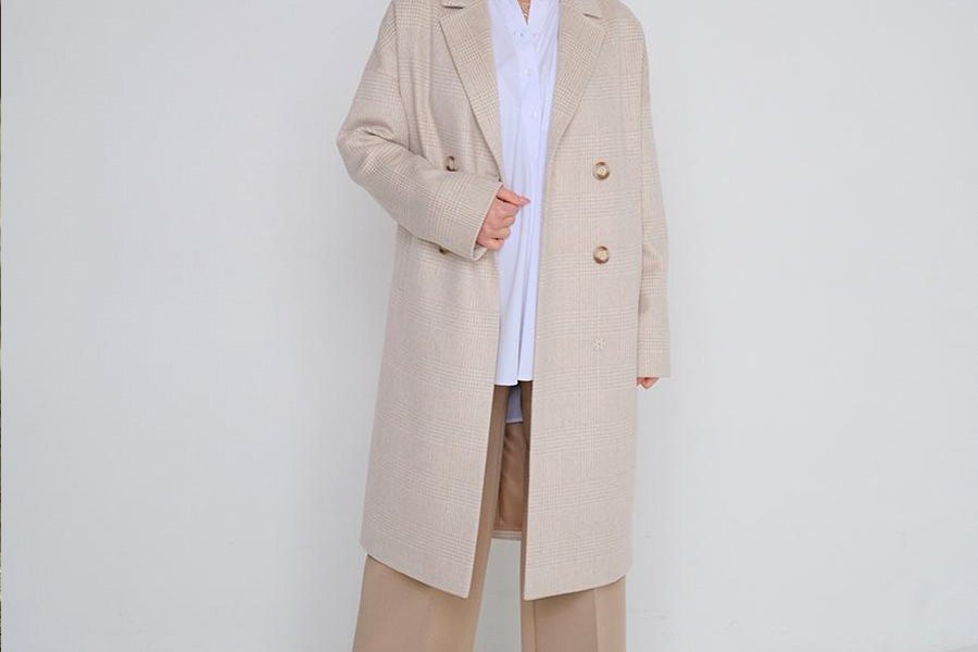 Lady in beige coat and white top rocking beige pants