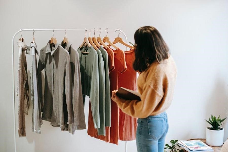 Lady in brown checking clothes on a hanging rack