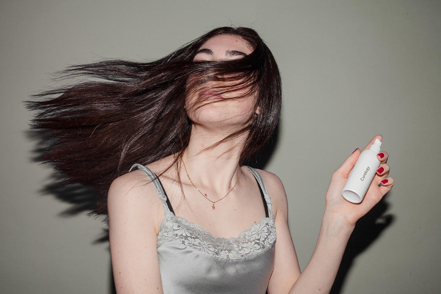 Person holding hair serum to fix damaged hair