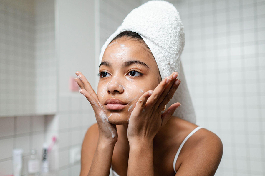 Young woman applying foaming facial cleanser