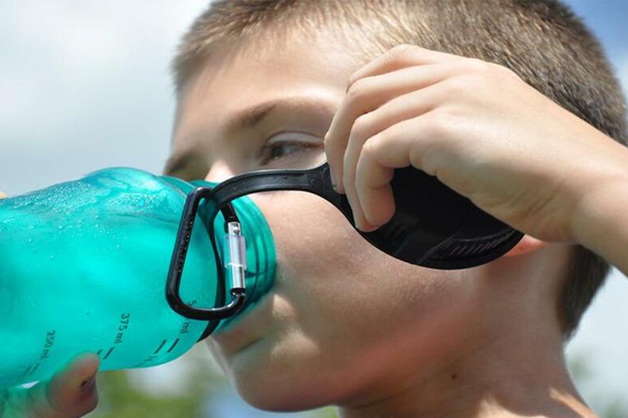 A boy drinking water from plastic sports water bottle