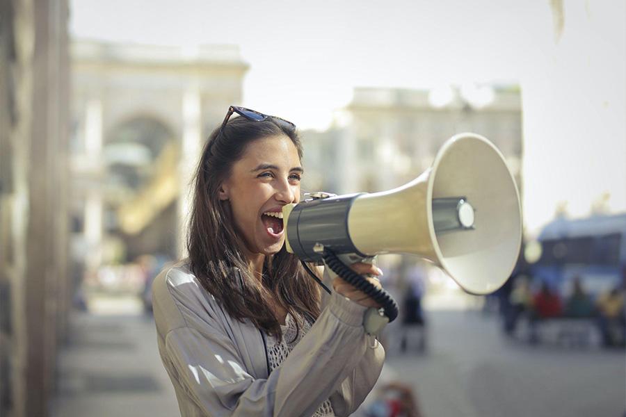 a cheerful lady using a megaphone to scream