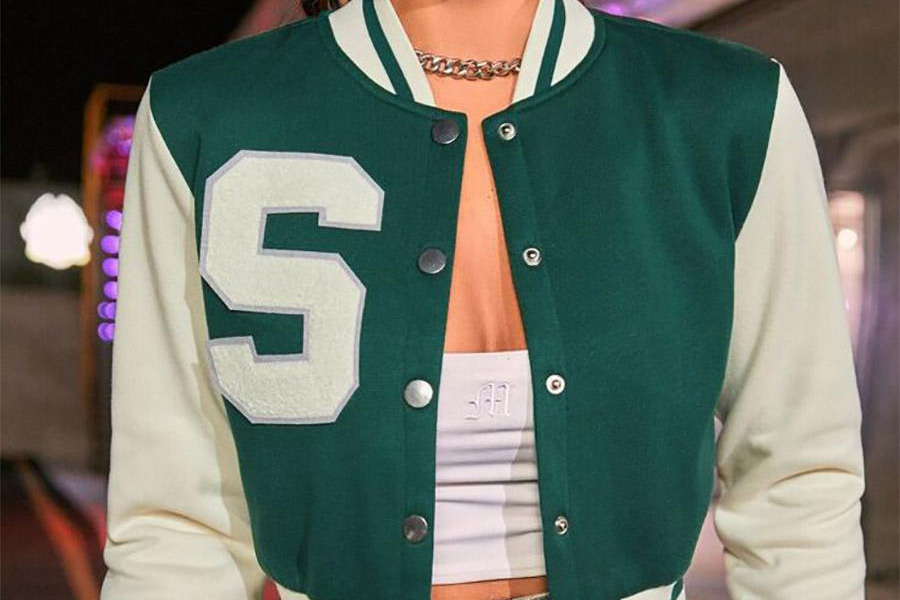 A lady wearing a green cropped letterman jacket